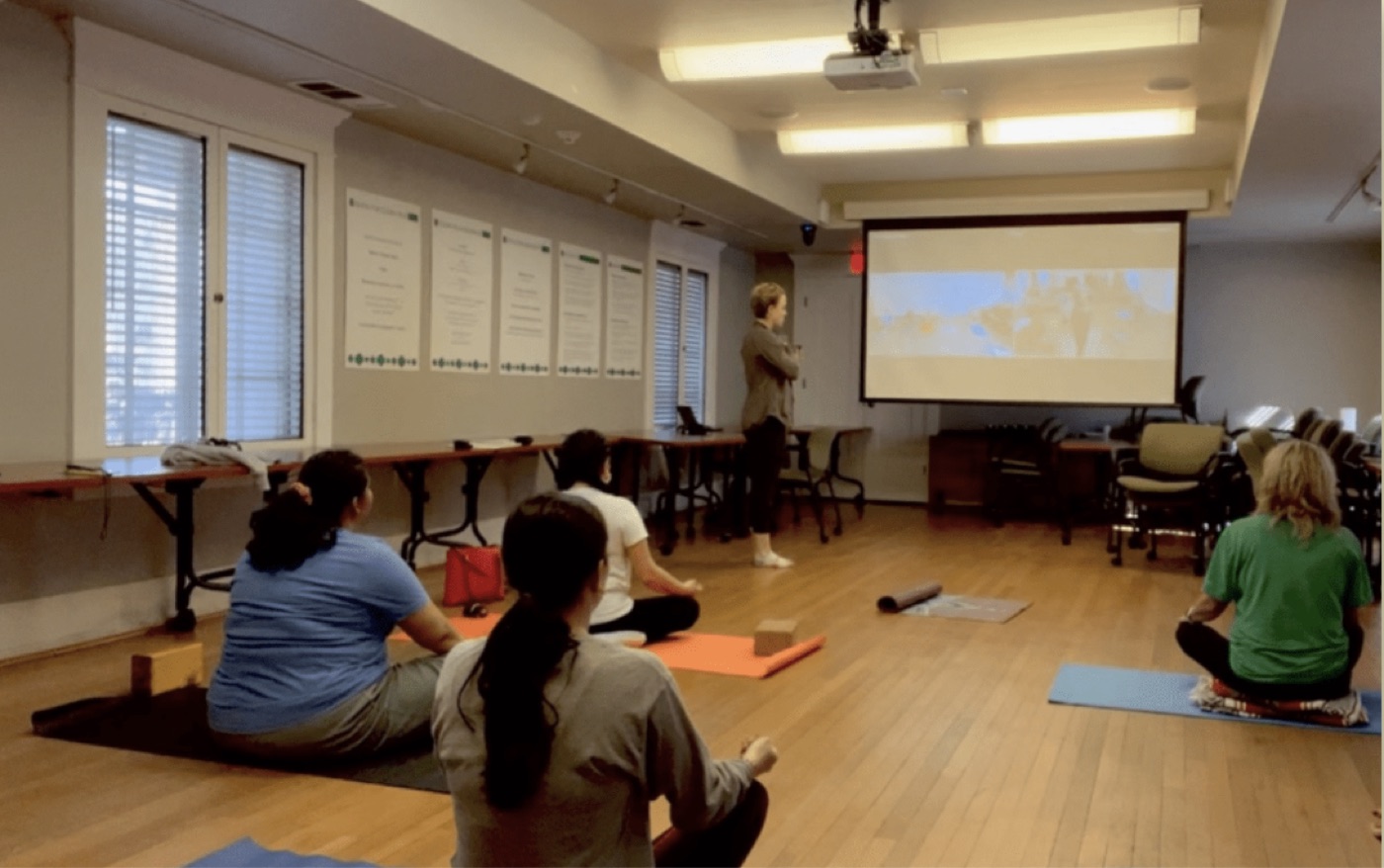 Employees joining a hybrid mindfulness and yoga session in a conference room