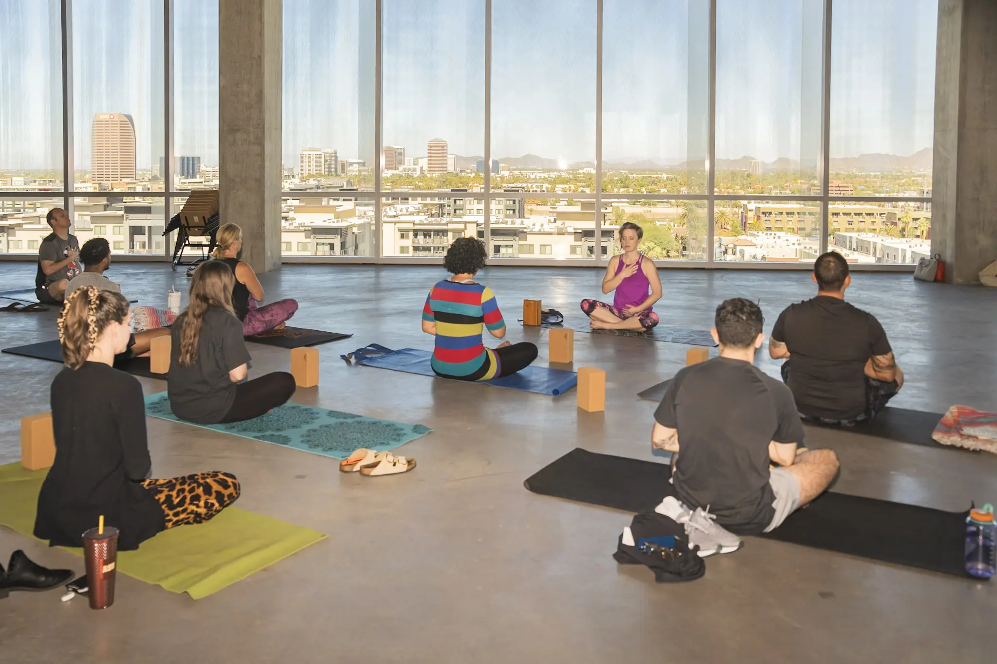 A yoga and mindfulness session taking place in a bright, high-rise workplace studio
